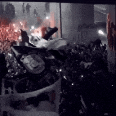 a crowd of people are gathered in a dark room with a sign that says ' i love you '