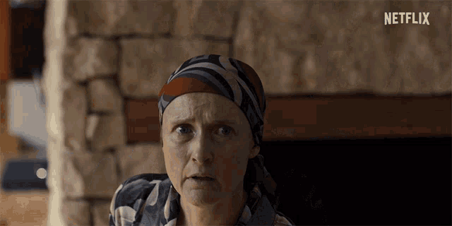 a woman with a scarf around her head looks at the camera with a netflix logo in the background