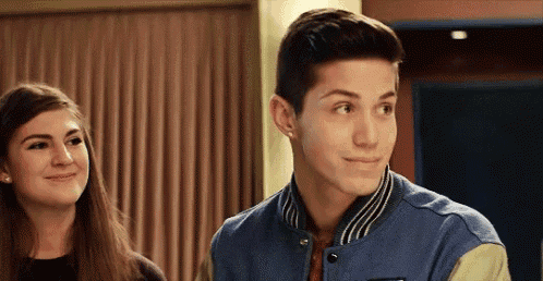 a boy and a girl are standing next to each other and the boy is wearing a blue varsity jacket