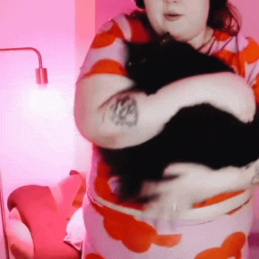 a woman with a tattoo on her arm is holding a cat