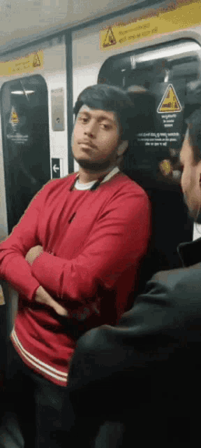 a man in a red shirt sits on a subway train