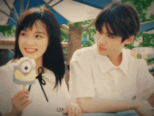 a girl holding an ice cream cone with a minion on it and a boy looking at her