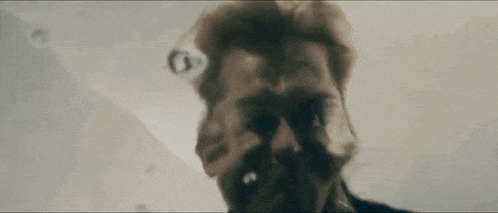 a close up of a man 's face with a beard looking up at the camera .