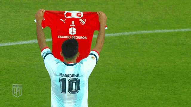a soccer player holds up a red shirt that says escudo seguros on it
