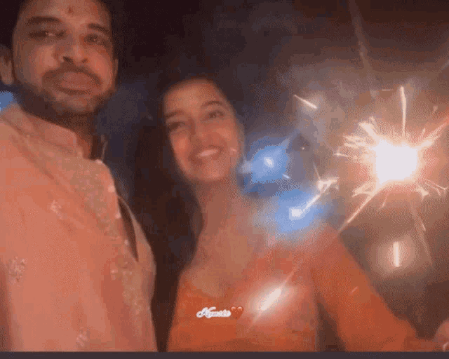 a man and a woman are posing for a picture with sparklers in their hands