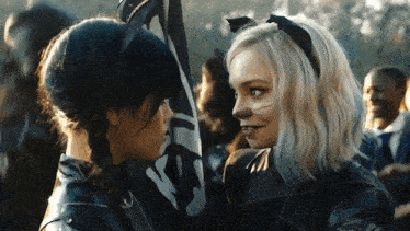a couple of women are standing next to each other and looking at each other .