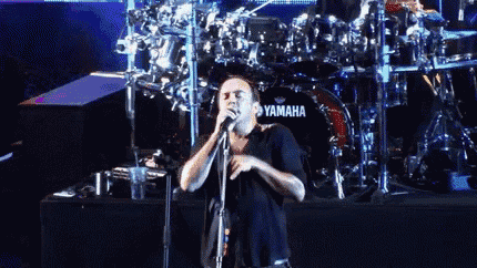 a man singing in front of a drum set that says yamaha