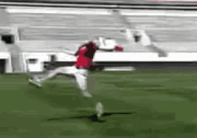 a soccer player in a red jersey is kicking a ball on a field .