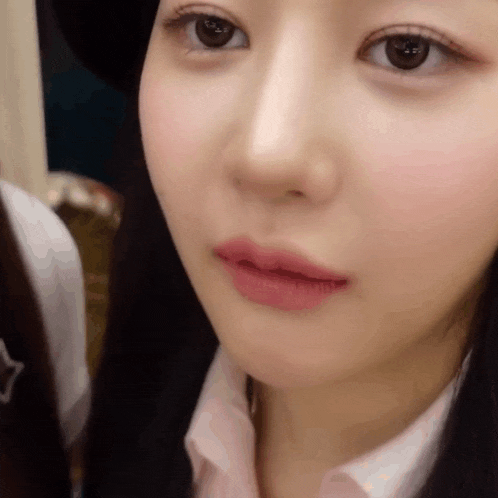 a close up of a woman 's face with a hat on and pink lipstick .