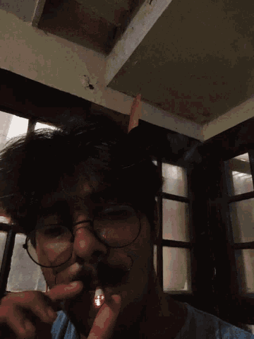 a man wearing glasses smoking a cigarette with a red light coming out of his mouth