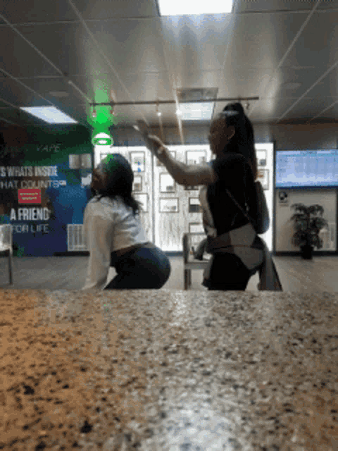 two women standing in front of a vape sign