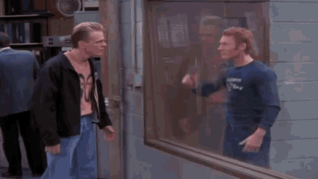 two men are standing in front of a window and one of them is wearing a shirt that says runner