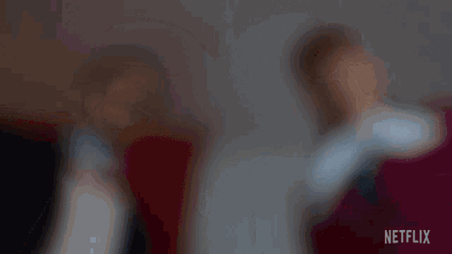 a blurry picture of two people sitting next to each other with netflix written in the corner