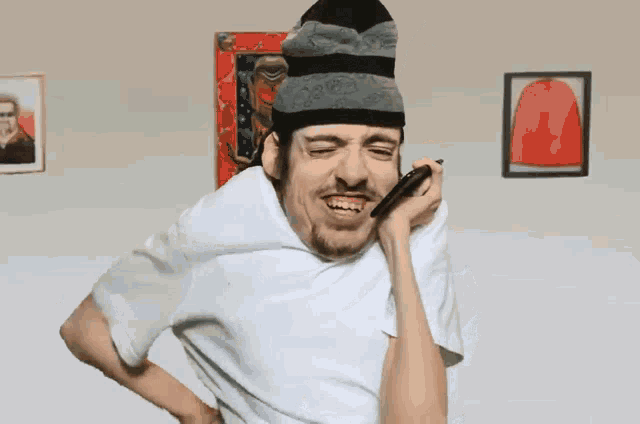 a man wearing a beanie and a white shirt is blowing into a straw