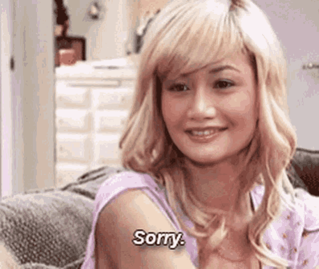 a woman with blonde hair is sitting on a couch and says sorry