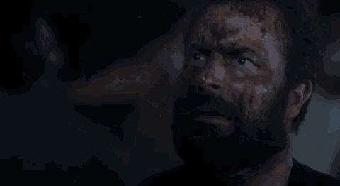 a man with blood on his face is looking at the camera .