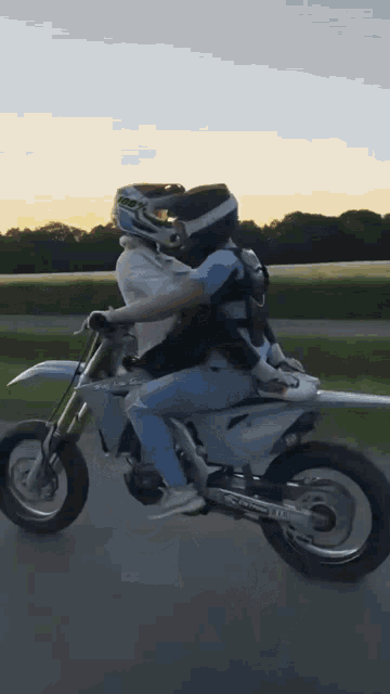 a person riding a dirt bike with a person sitting on the back