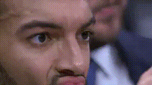 a close up of a man 's face with a man in a suit and tie behind him .