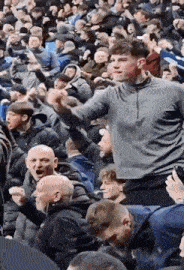 a man is being lifted in the air in a crowd of people at a soccer game .