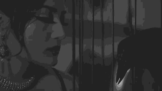 a woman is standing in front of a cage with a bird behind her .