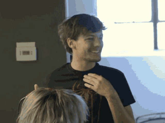a man wearing a black shirt with a spider on it smiles