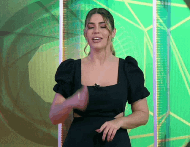 a woman in a black dress is standing in front of a green wall