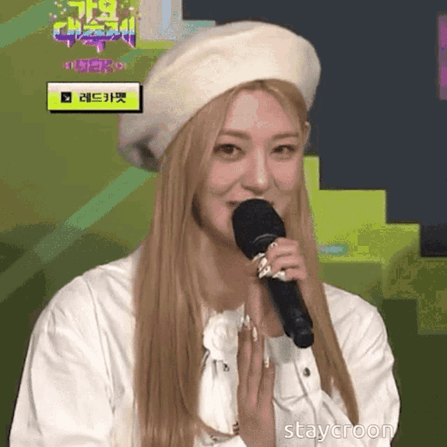a woman wearing a white beret is holding a microphone in front of her mouth
