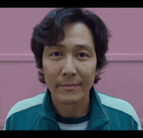 a close up of a man 's face with a pink wall behind him