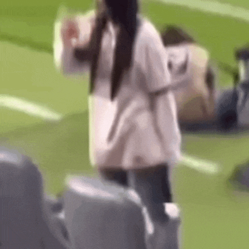 a woman is standing on top of a soccer field holding a bottle of water .