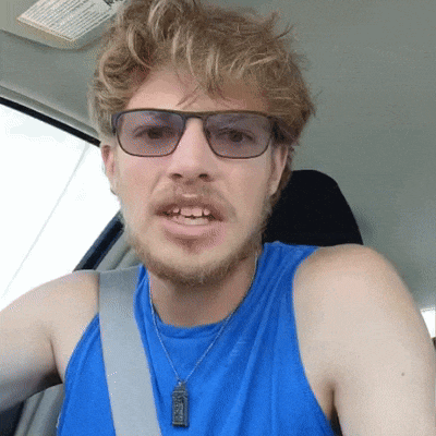 a man wearing glasses and a blue tank top has a necklace with a pendant that says jesus on it