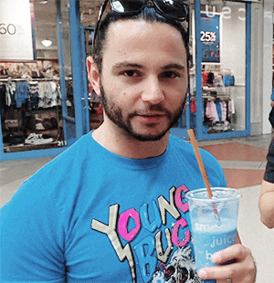 a man wearing a blue shirt that says young bug is drinking from a cup with a straw