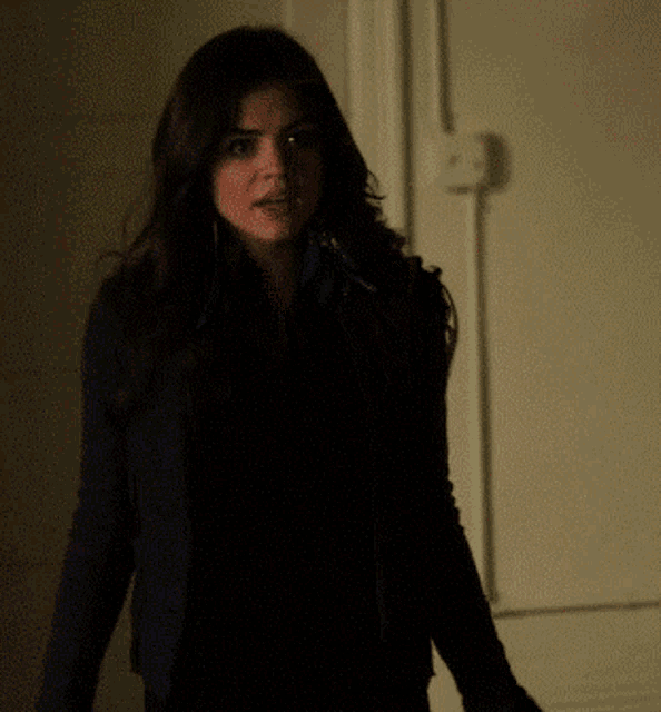 a woman in a black jacket is standing in front of a white door