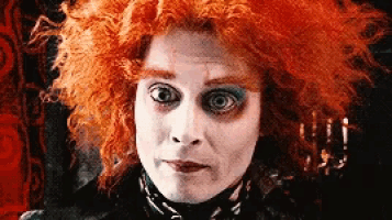 a close up of a person with red hair and white makeup .