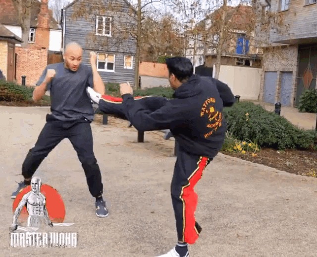 a man wearing a master john hoodie kicks another man in the face