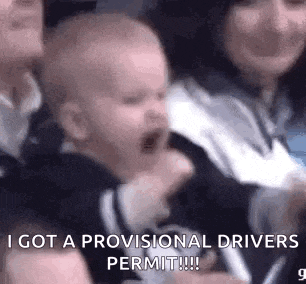 a baby is crying in a crowd of people and a woman is holding him .