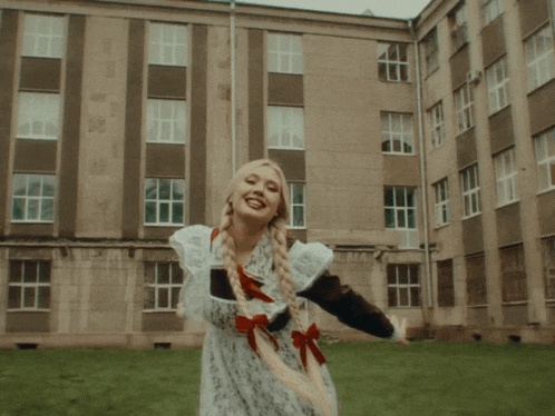 a girl in a school uniform stands in front of a large building