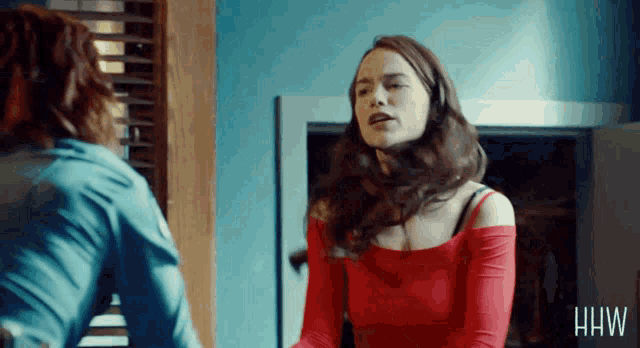 a woman in a red top is standing next to another woman in a blue shirt with the letters hw on the bottom right
