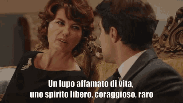 a man and a woman are sitting on a couch and the woman is saying " un lupo affatto di vita "