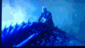 a blurry picture of a person sitting on a rock in the ocean .
