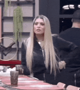 a woman with long blonde hair is sitting at a table in a restaurant .