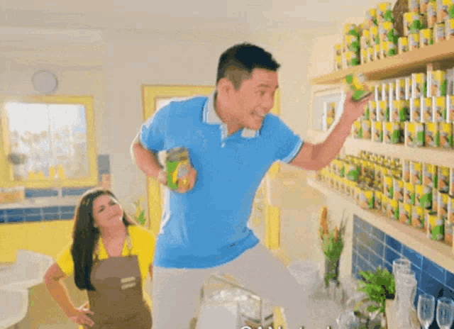 a man in a blue shirt is standing in front of a woman in an apron