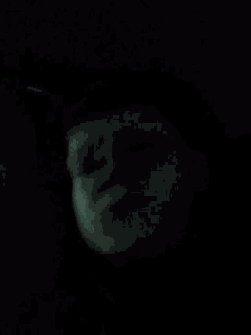 a close up of a person 's face in the dark with a light shining on it .
