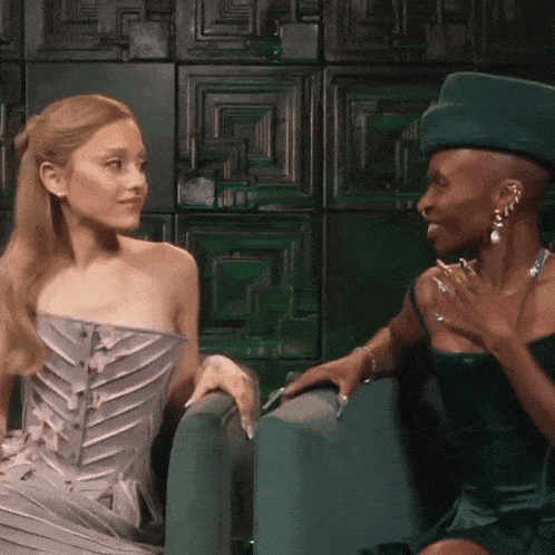 a woman in a green hat sits next to another woman in a gray dress
