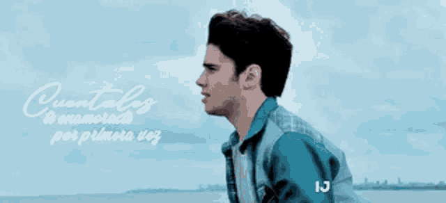a man in a blue jacket is standing in front of a body of water with the words " cuentales to enamorado por primera vez "
