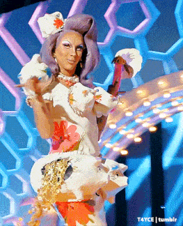 a drag queen is dancing on a stage with a flamingo in her hand ..