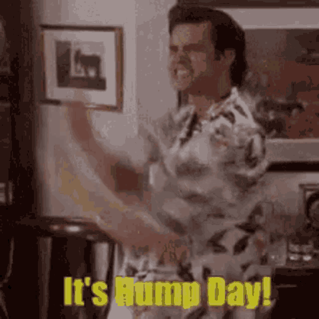 a man is dancing in a living room with the words `` it 's hump day '' .