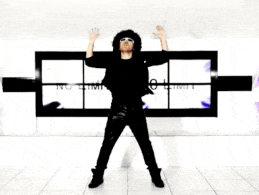 a man with an afro wearing sunglasses and a black shirt stands with his arms outstretched