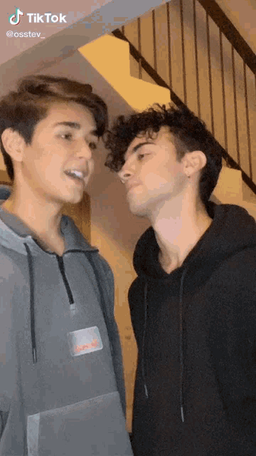 two young men are standing next to each other in front of a staircase with tiktok written on the bottom
