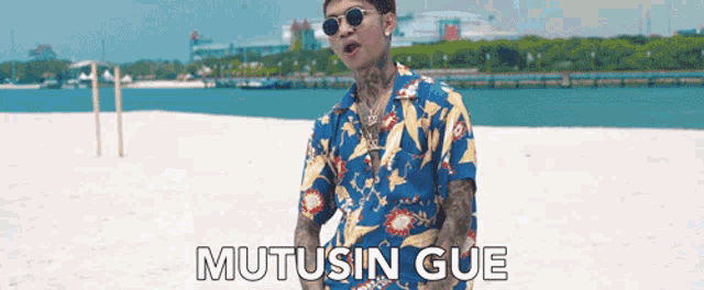 a man is standing on a beach with the words mutusin gue written on the bottom