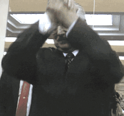 a man in a suit and tie holds his hands up in the air